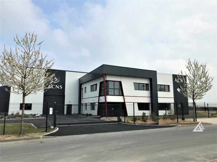 Vue extérieure depuis la route d'un bâtiment de bureaux et atelier construit à Milly-la-Forêt (91) avec le logo ACNS